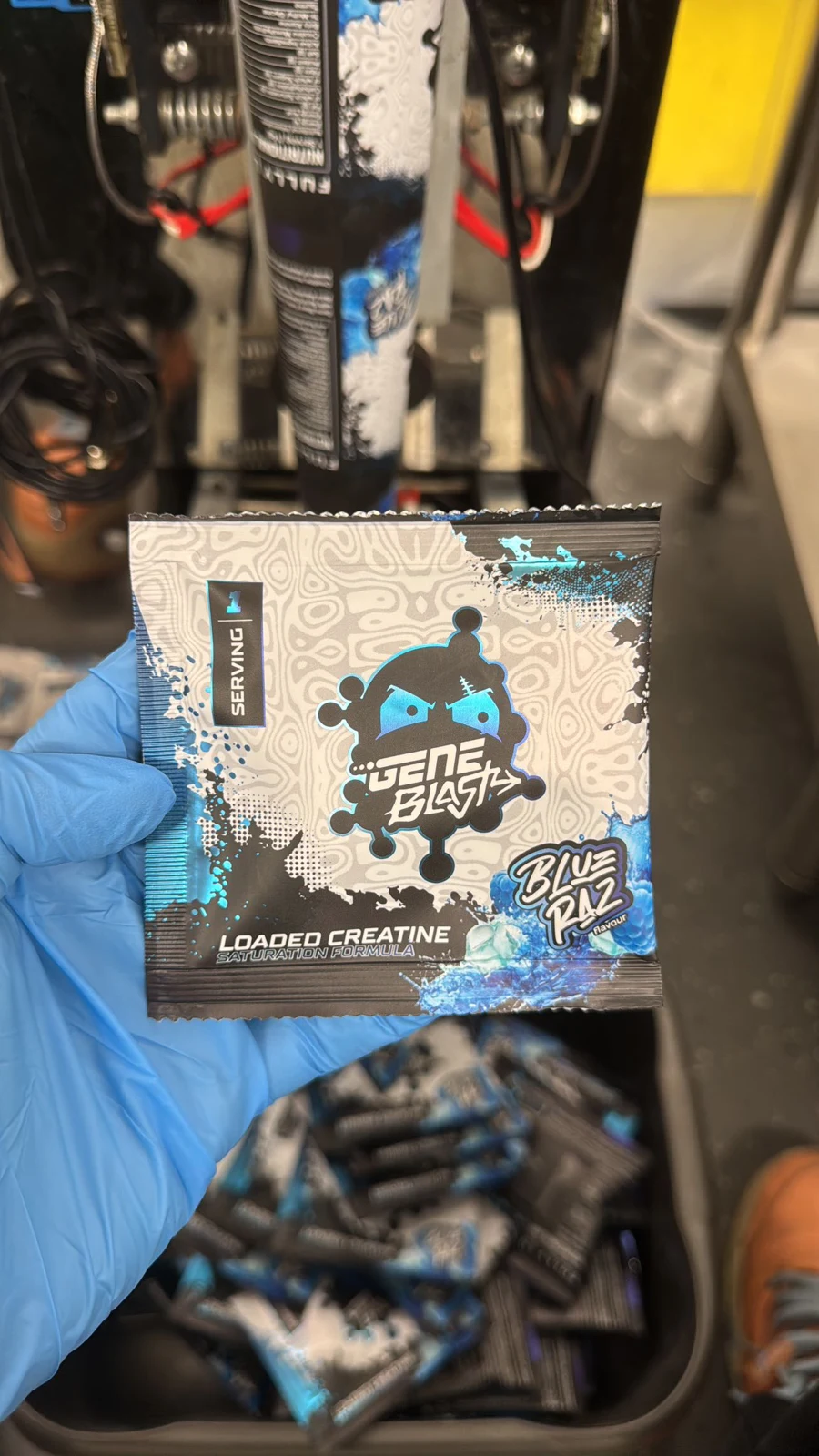 Blue Raz creatine sample sachet held in a blue gloved hand