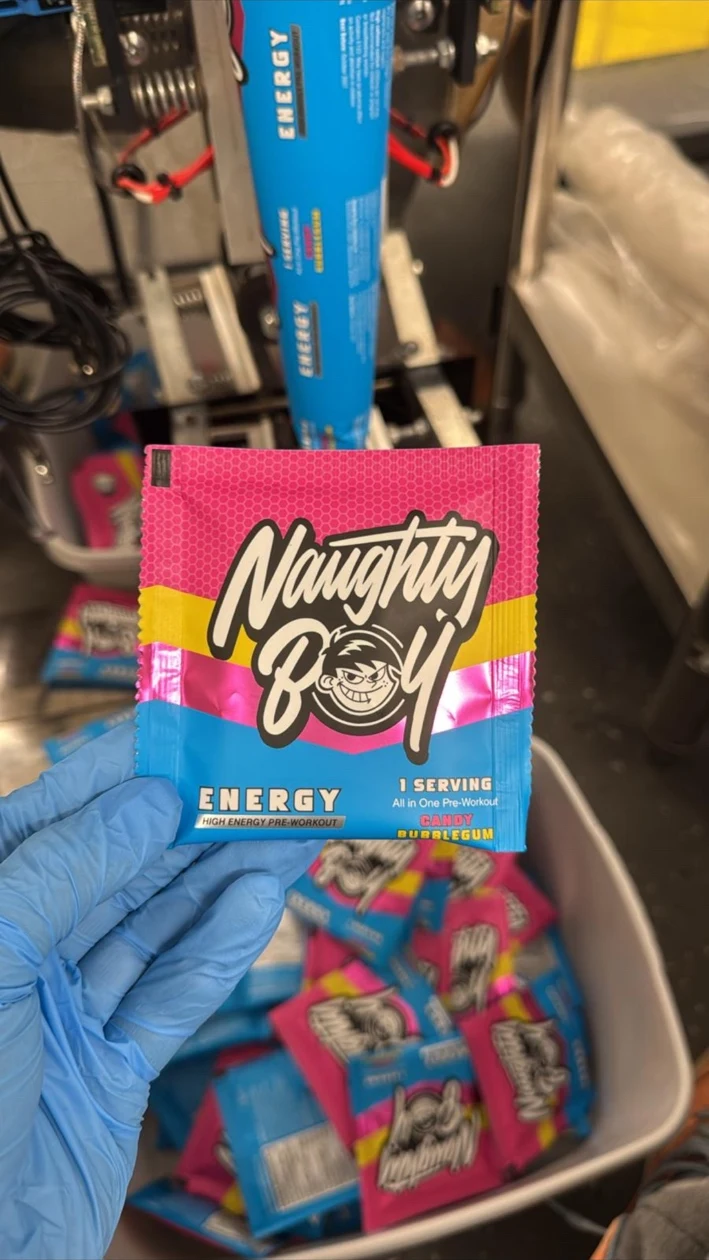 Energy pre-workout sample sachet held in a blue gloved hand