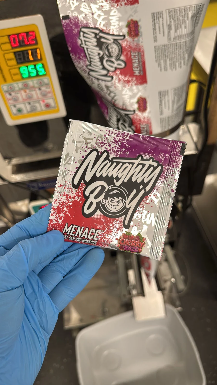 Menace Cherry Razz sample sachet held in a blue gloved hand